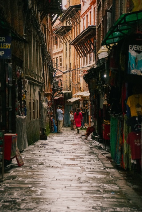 A rain-slicked alley in old Kathmandu lined with shops
