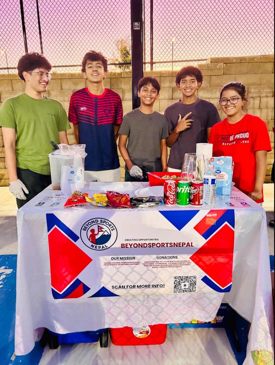 The BeyondSportsNepal founding team smiling behind a fundraising booth