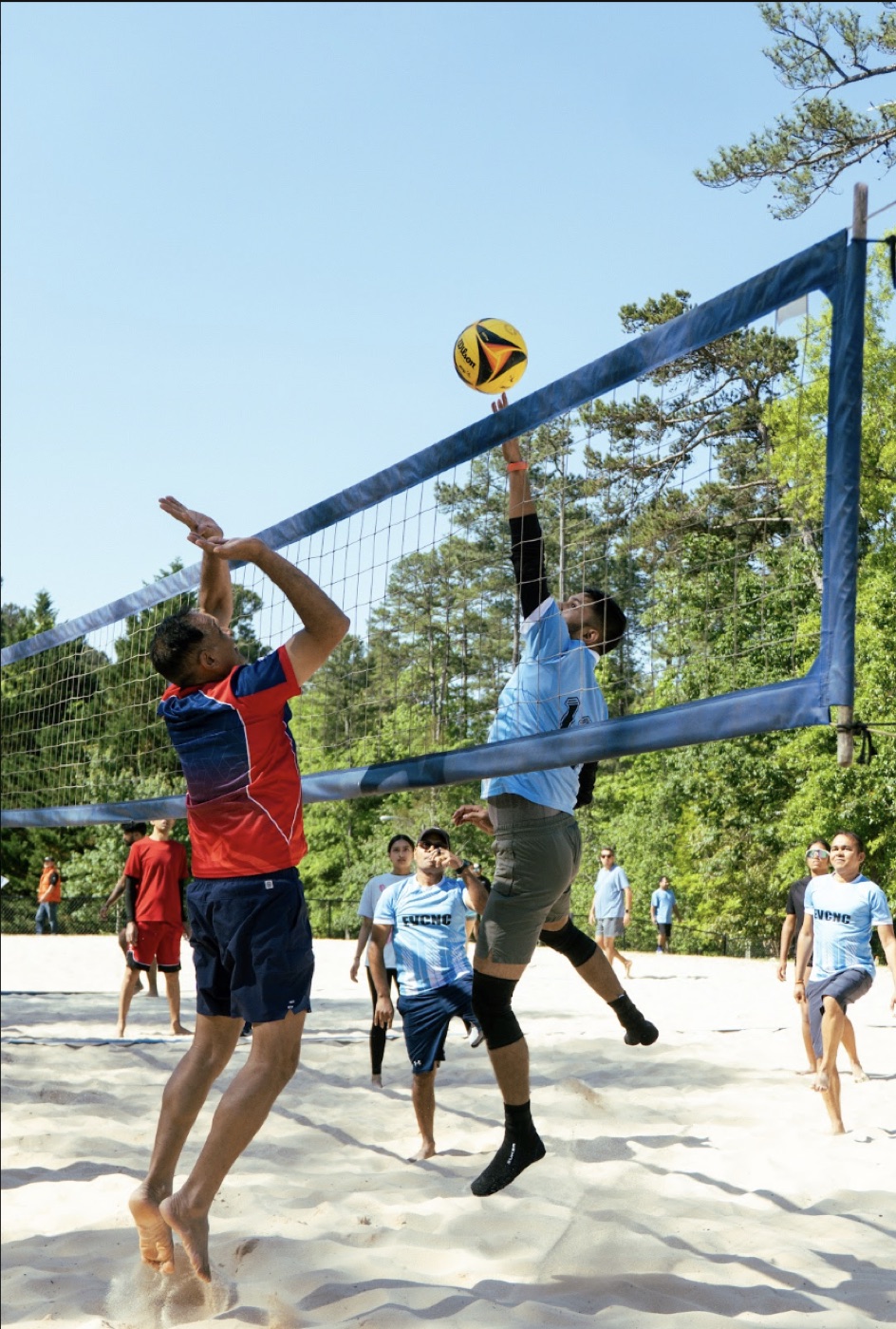 Players leaping at the net during a beach volleyball match